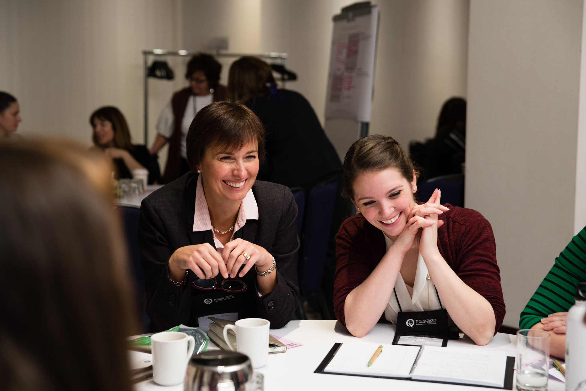 Two women smile during a group discussion at the BC Quality Forum.